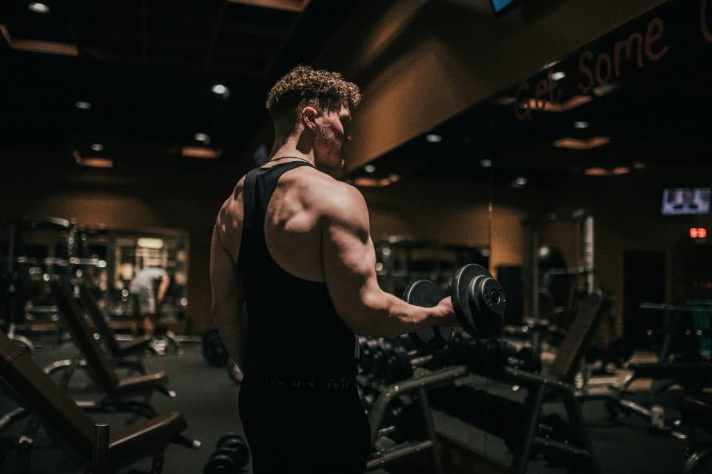 Athlete performing a dumbbell curl in a dimly lit gym